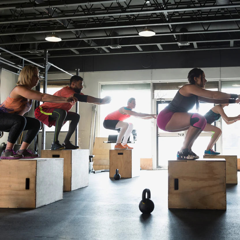 Group of people performing box jumps in a gym setting