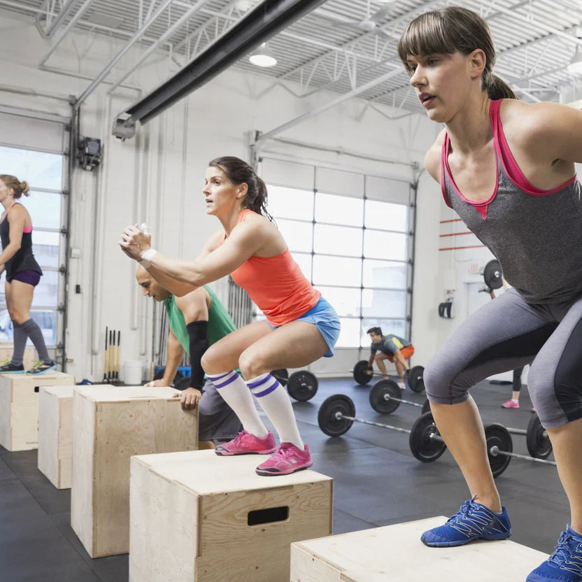 Group of women exercising on boxes in a gym setting